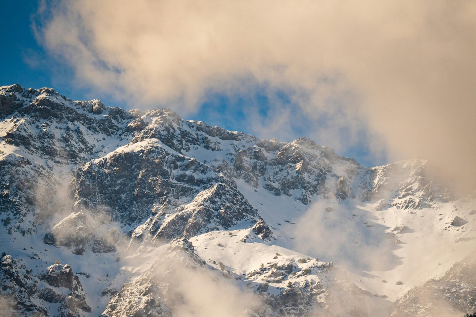 Scenic view of the snow-covered Andes Mountains with clouds, captured in Santiago, Chile.