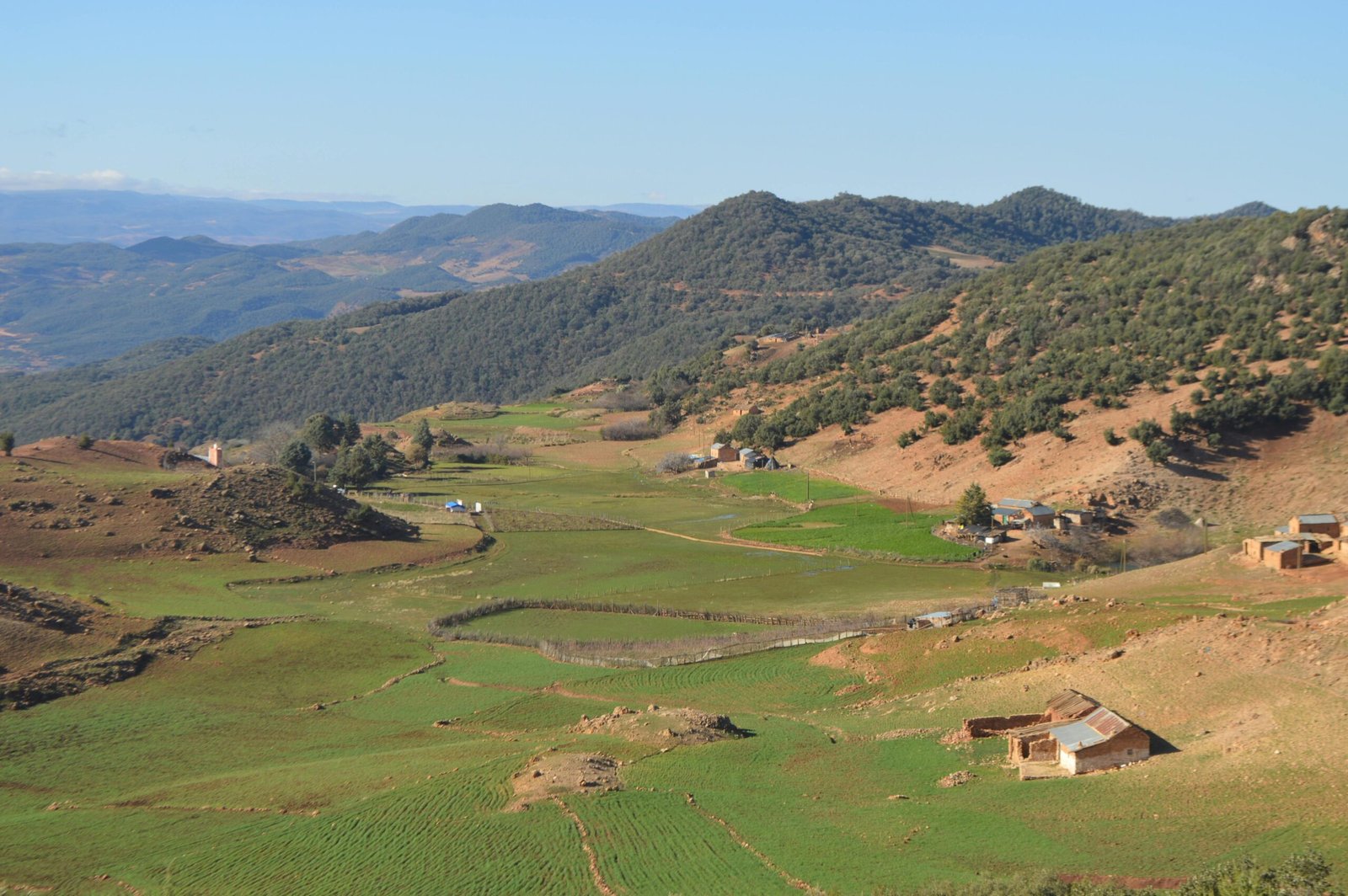 Picturesque mountain valley with lush green fields and scattered rural homes.