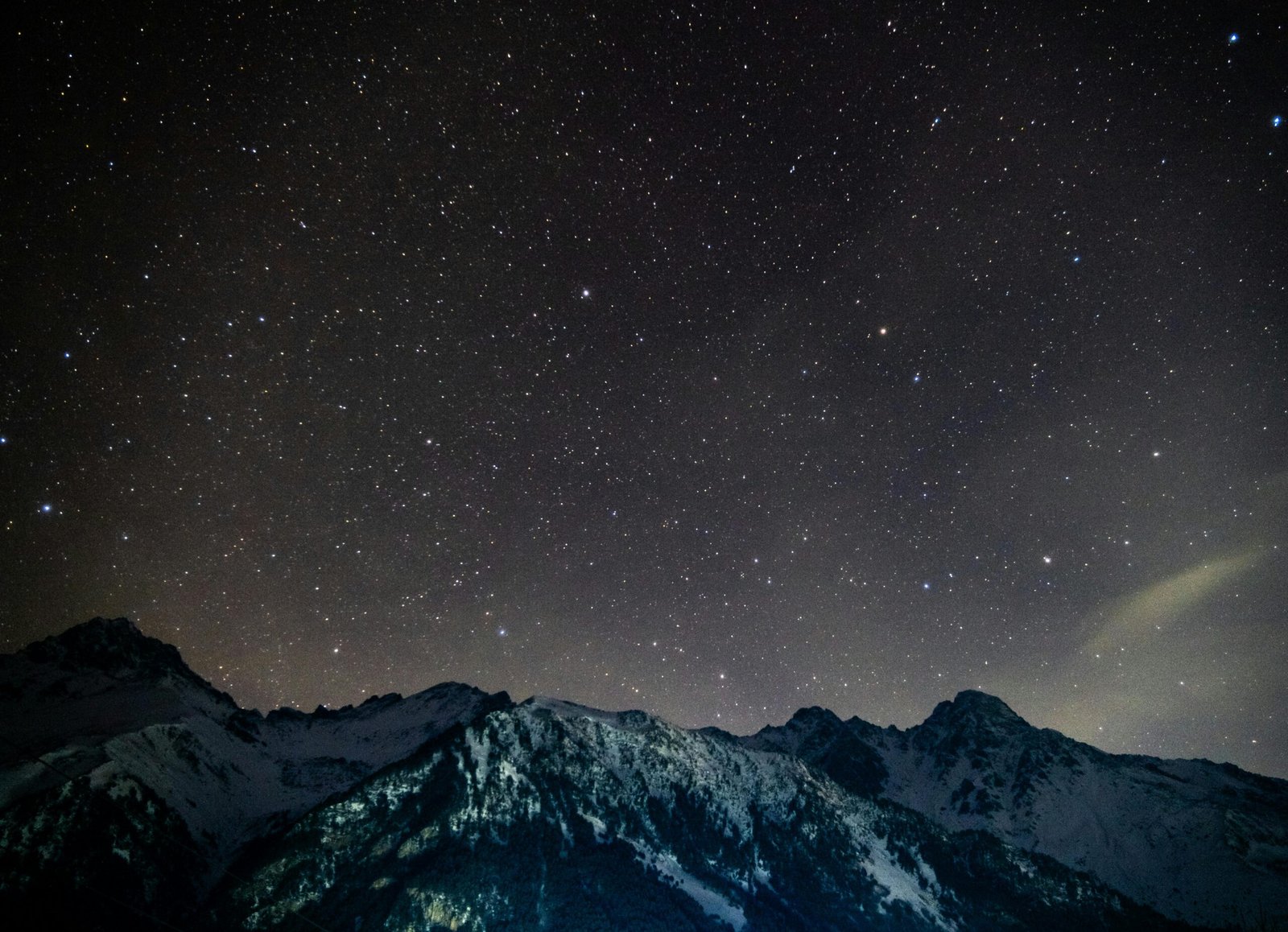 A breathtaking view of the starry night sky over snowy mountains under the dark night.