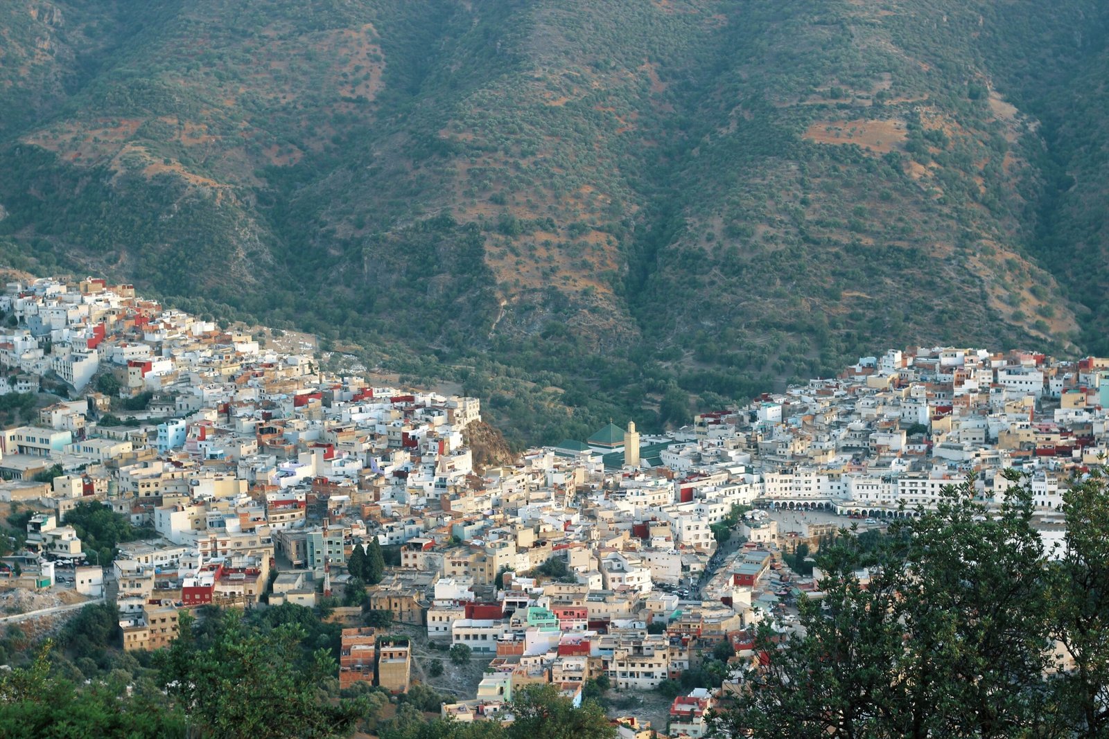 Stunning aerial view of the colorful town of Chefchaouen nestled in lush Moroccan mountains.