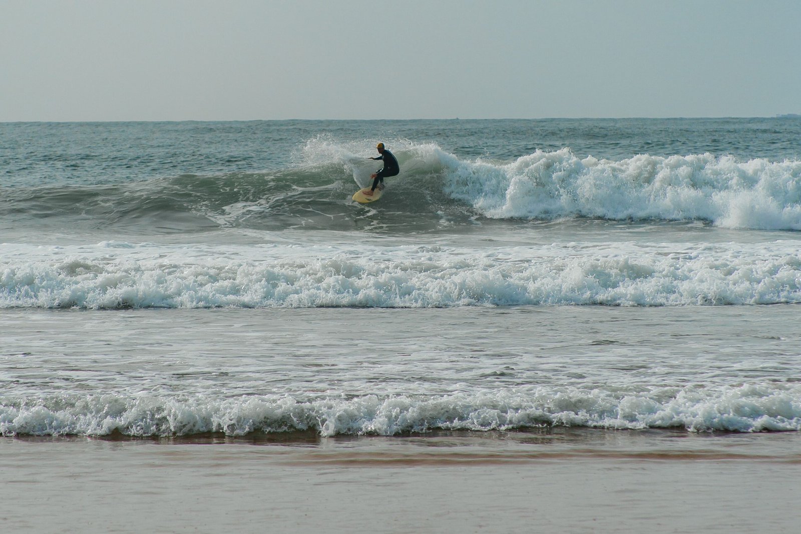 A surfer skillfully catches a wave, enjoying ocean surfing on a sunny day.